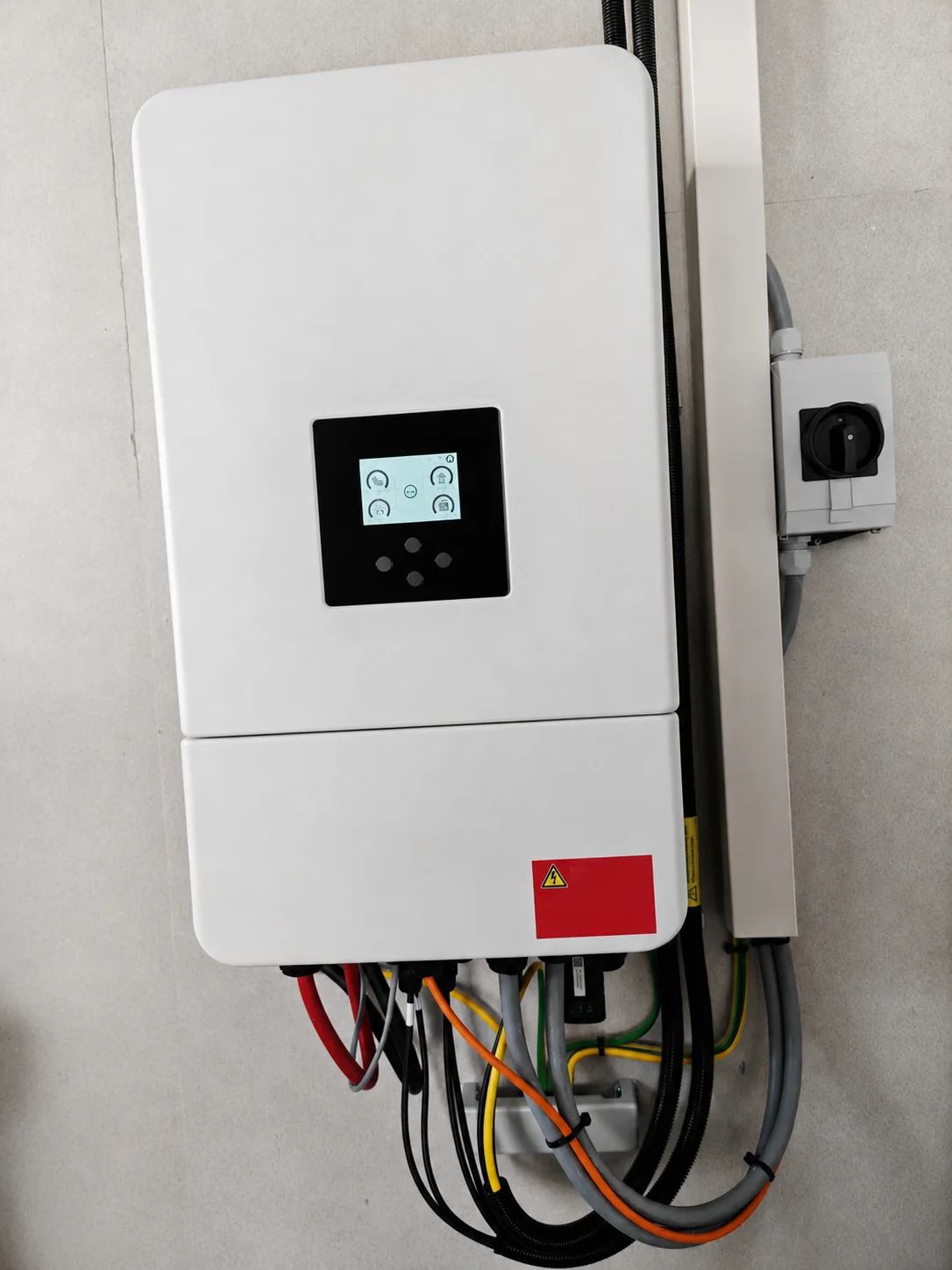 Nahaufnahme eines weißen Hybridwechselrichters mit Display und angeschlossenen Leitungen