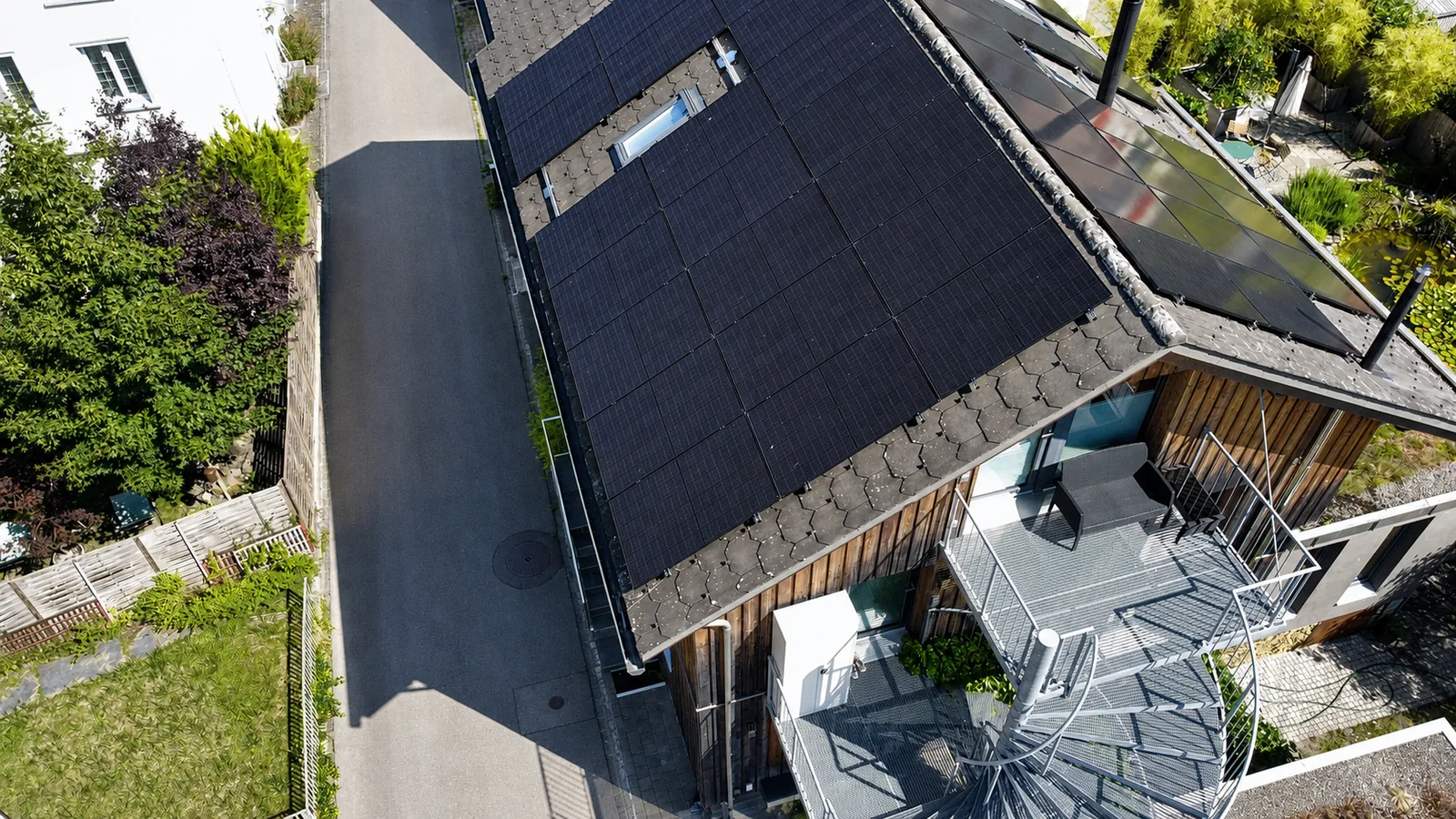 Drohnenaufnahme schwarzer Photovoltaikmodule auf einem modernen Holzhaus