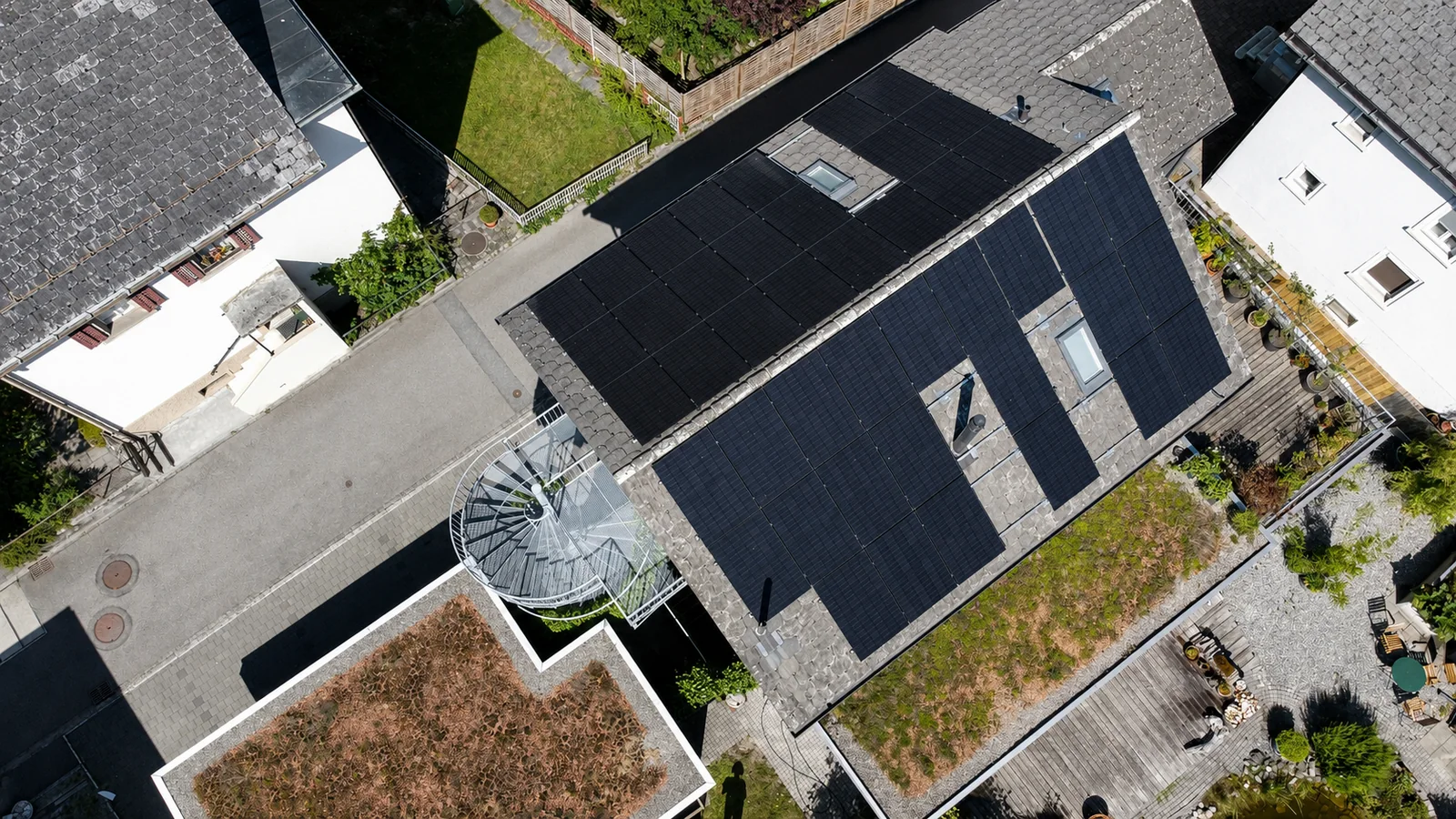 Senkrechte Drohnenansicht einer Photovoltaikanlage auf einem Stadthaus mit Flachdachbegrünung