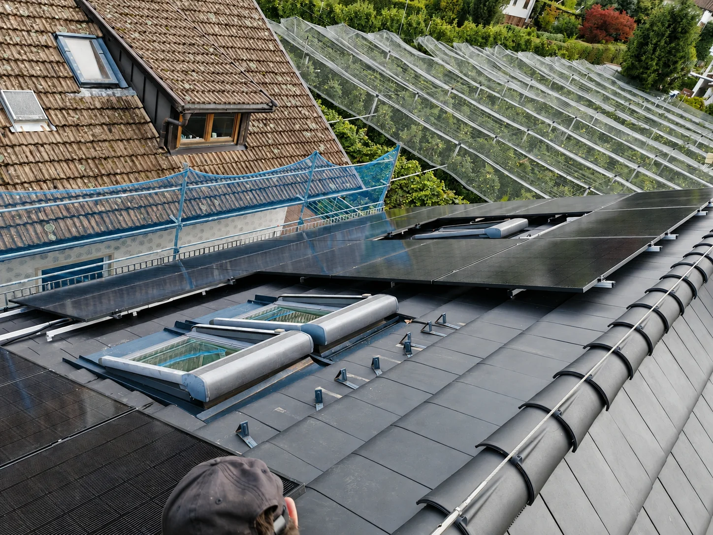 Photovoltaikmodule und Dachfenster während der Montage neben Gewächshäusern