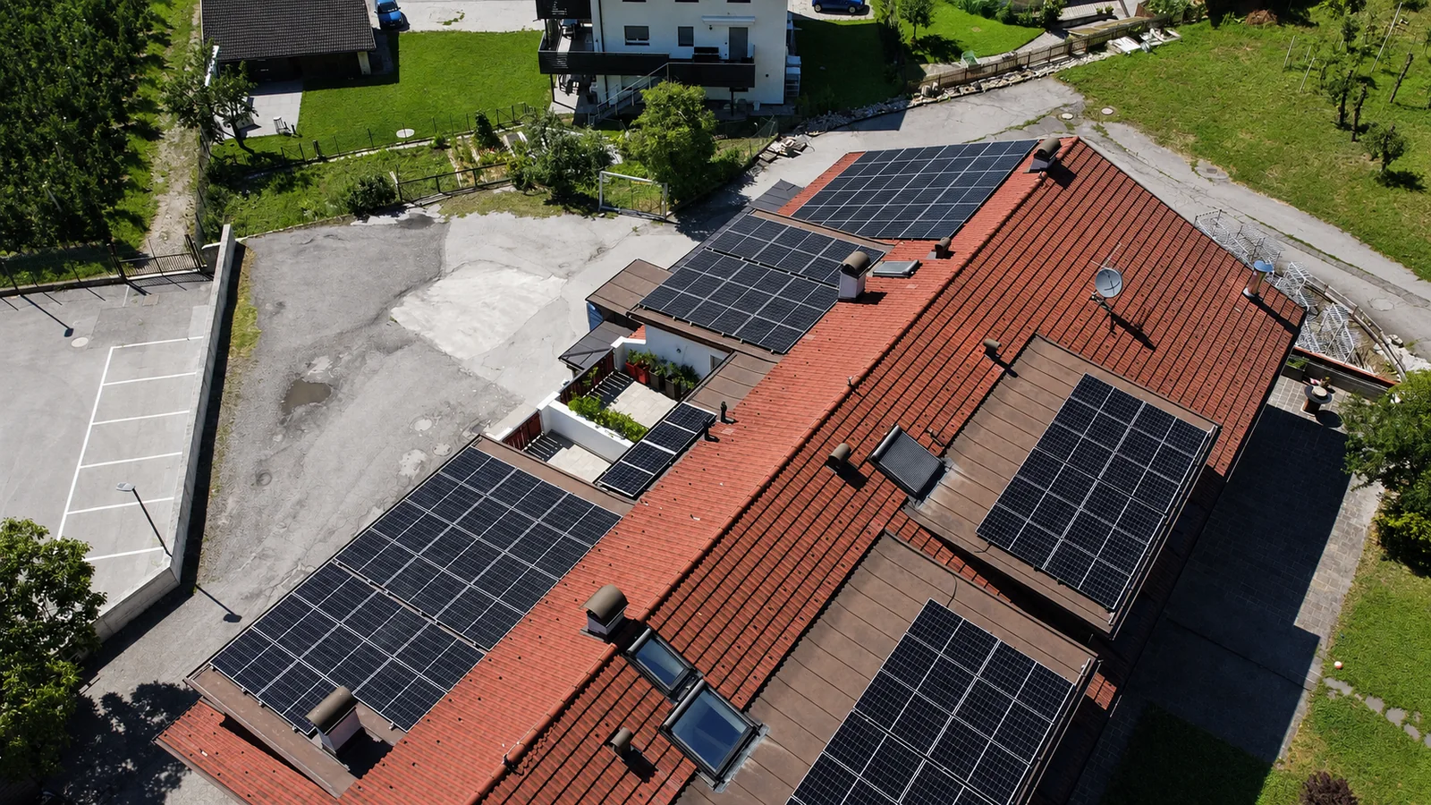 Drohnenaufnahme eines großen roten Daches mit mehreren Photovoltaikfeldern